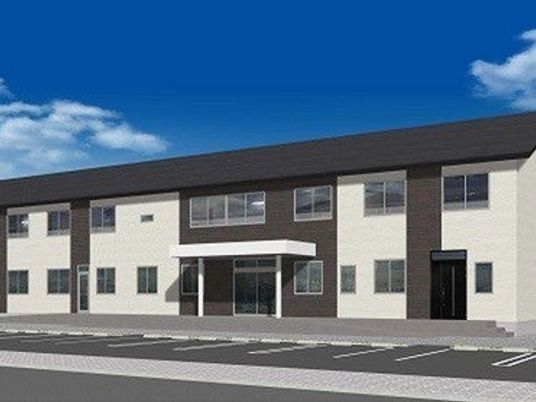 白と黒のスタイリッシュな外観。2階建ての建物の前には広い駐車スペースもある。