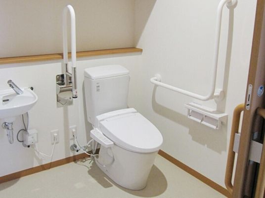 可動式・固定式の手すりがついた介護仕様のトイレの様子