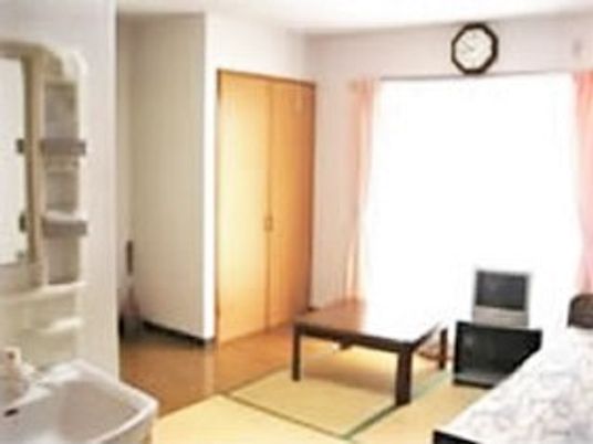 畳スペースが設置された居室には寝具付きのベッドやテレビ、テーブルがあり、洗面所も設置されている。