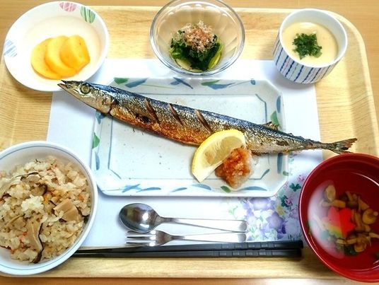 サンマの塩焼きに炊き込みご飯、吸い物、茶碗蒸し、青菜のお浸し、沢庵などが並んでいる。