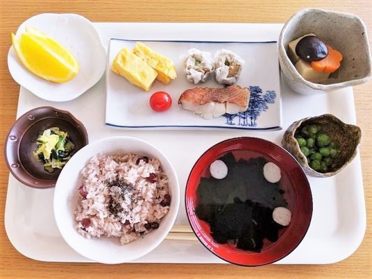 赤飯にフルーツ、煮物に焼き魚など種類豊富に並べられた食事。