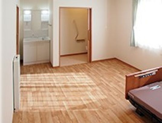 フローリングの居室には介護用ベッドや洗面、トイレなどが設置され、大きな窓もある。