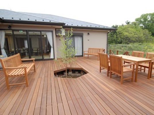 平屋建ての建物と外側の大きなウッドデッキ。施設内のリラックススペース