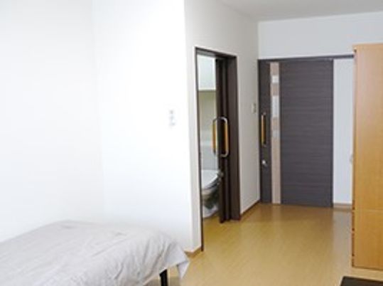 フローリングの居室にはベッドやトイレ、家具が付き、すっきりとしている。