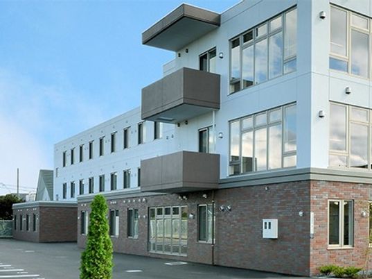 3階建ての建物は横に長く各フロアにベランダもあり、1階部分はレンガ調の外壁を使用している。