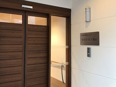 濃い色合いの樹のドアがついている施設の入り口付近。モダンなデザイン