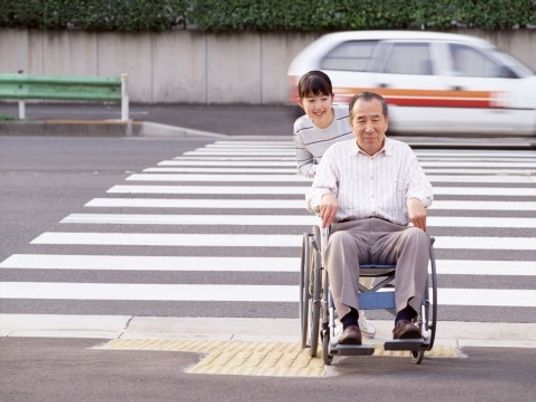 横断歩道を渡っている車いすの高齢者とそれを押している女性