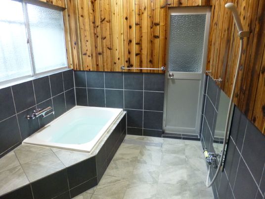 大理石風のフロアを採用した浴室には個浴槽とシャワーが付き、ベンチ代わりになる小上がりもある。