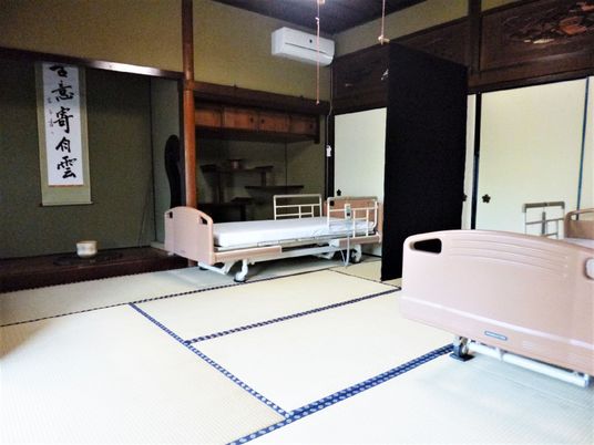 畳敷きの部屋には二つの介護ベッドが並び、床の間には掛け軸が飾られている。