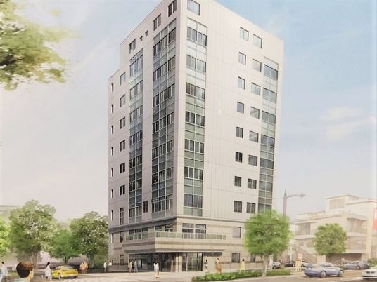 白を基調とした大きな建物。周辺には人や車の行き来があり、自然も適度に残っている。