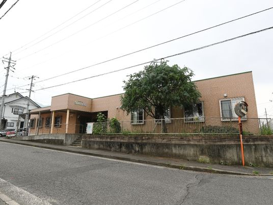 少し引いたアングルから見た建物の全景。奥に向かってやや上り坂になっており、建物の手前部分には立ち木が植わっている。