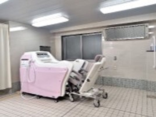 白とピンクの機械浴が設置されている広い浴室にはパネルヒーターもある。座ったまま入浴可能。