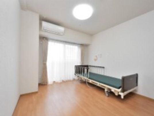 フローリングの部屋には介護ベッドやエアコン、緊急通報装置が付いている。おおきな窓がある。