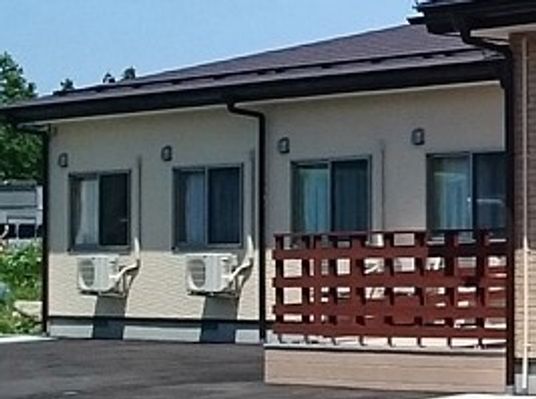 ウッドデッキがついた平屋建ての建物。周囲には緑が多くある。