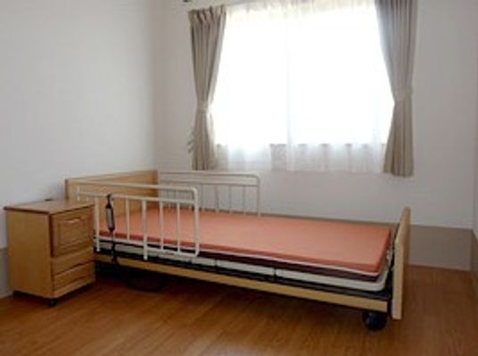 居室にはベッドと収納棚が置かれ、大きな窓があり明るい雰囲気。