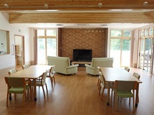 木のぬくもりが感じられる館内には木製の５人掛けのテーブルが複数あり、テレビを囲んだソファスペースもある。