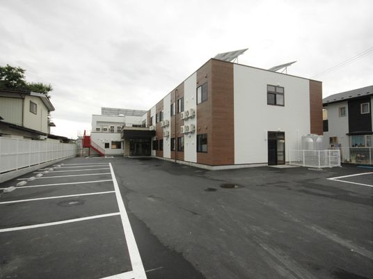 駐車場スペースが広めの敷地。ツートンカラーが印象的な建物が写っている様子