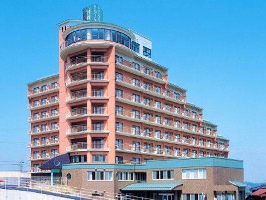 オレンジ系の外壁の10階建ての建物の一番上のフロアはガラス張りで、周りに背の高い建物はなく、日当たり良好。