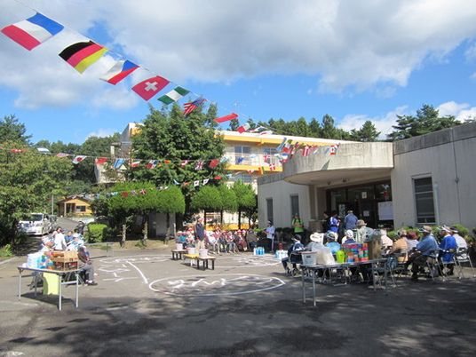 運動会の旗が取り付けられた小さな広場。高齢者が運動会をしている様子