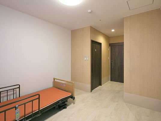 介護ベッドが置かれた部屋にはトイレのドアもあり、天井にはスプリンクラーや照明もある。