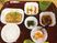 おかゆや卵料理、豆腐、青菜の和え物などが並んだブラウンのトレー。