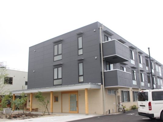 3階建ての建物はコンクリート製でどっしりとした頑丈な建物。2階と3階はグレー1階はベージュ。