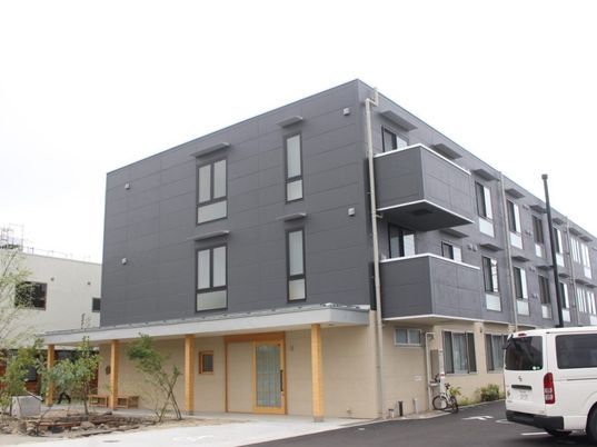 3階建ての建物はコンクリート製でどっしりとした頑丈な建物。2階と3階はグレー1階はベージュ。