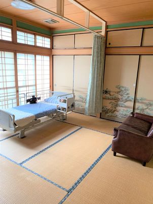 和室仕様の居室のようす。介護用ベッドとソファが置いてある施設内の居室