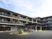 3階建ての建物はブラウン系で敷地内には駐車場があり、日当たりのいい場所に建っている。