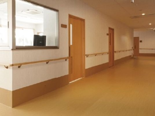 隙間なく手すりが取り付けられている施設内の廊下の様子。個室のドアが写っている