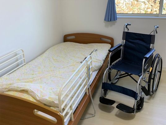 ベッドと車いすが置かれている施設内の一室。オールバリアフリーの床の様子