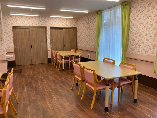 食堂には4人掛けのテーブルが並び、大きな窓にはカーテンが付き、壁には花柄の壁紙が貼られている。