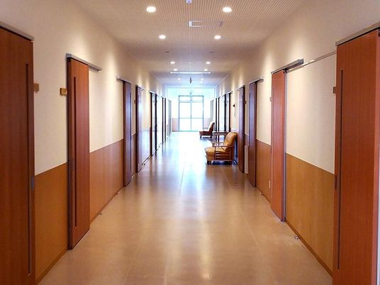 まっすぐな廊下の両サイドには居室のドアが並び、ドアのそばには表札のような小さなプレートが貼られ、ソファも壁際にいくつか置かれている。