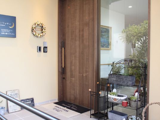 木製のドアが設置され、植物やリースが飾られているアットホームな雰囲気のエントランス。