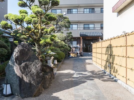 ４階建ての建物に続く道のサイドには本格的な和風庭園があり、建物の玄関には瓦の屋根がある。