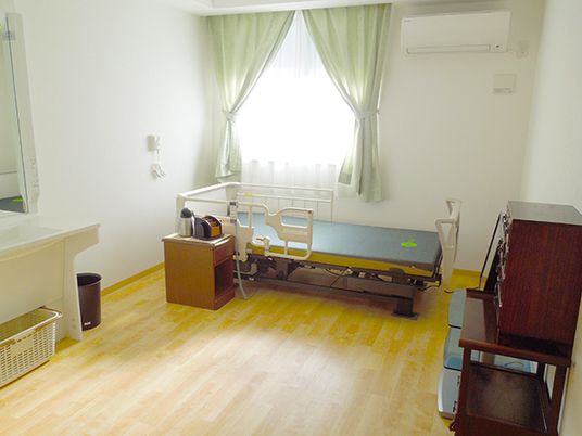奥の方にベッドが置いてある施設内の居室。右側に調度品が置いてある様子