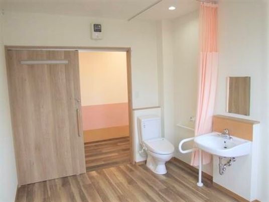 施設内の居室の入り口とトイレ、洗面台の写真。施設内の設備の様子