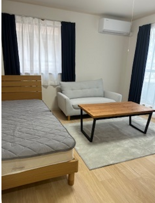 ベッドとソファ、テーブルが設置されている居室