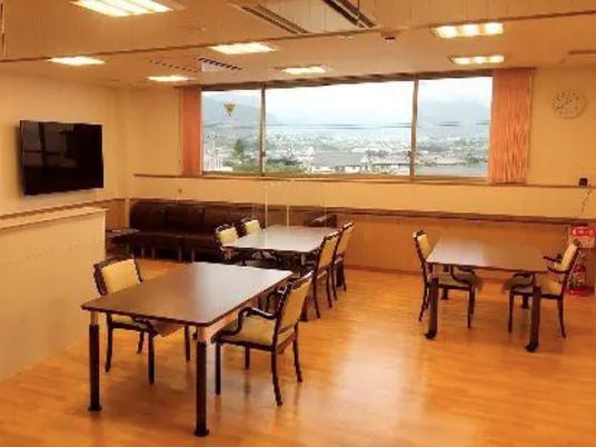 壁掛けテレビや少人数用のダイニングテーブルが複数置かれ、大きな窓がある食堂。窓の外には街並みを見ることができる。