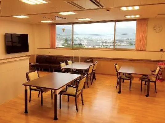壁掛けテレビや少人数用のダイニングテーブルが複数置かれ、大きな窓がある食堂。窓の外には街並みを見ることができる。