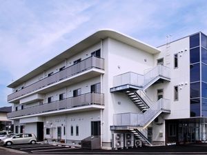３階建ての建物は白を基調としていて、ベランダや屋外階段が付いている。