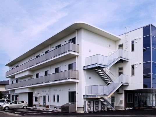 ３階建ての建物は白を基調としていて、ベランダや屋外階段が付いている。