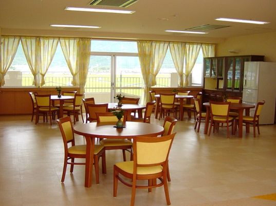 丸テーブルと椅子のセットが複数並べられている施設内のリビングスペース