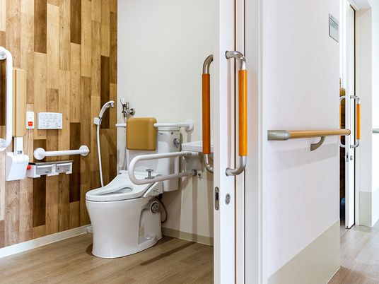 手すりがついた介護仕様のトイレの様子。引き戸で仕切られた広めのトイレ