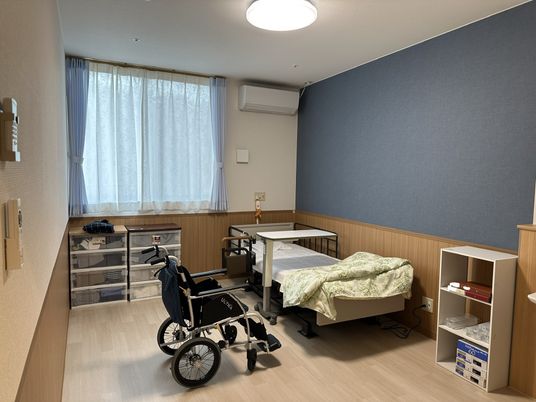 介護用ベッドと車いす、収納用品や棚が置かれている部屋
