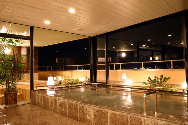 施設のお風呂。高級ホテルを思わせるような広々と開放的な大浴場。窓の外から夜景も見える。