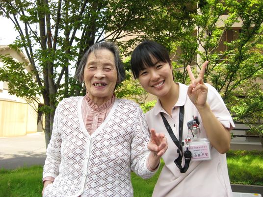女性利用者と女性スタッフが笑顔でピースをしてこちらを向いている。