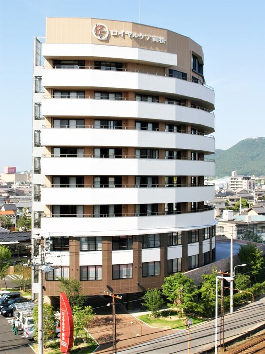 ロイヤルケア高松の外観、大きく立派な建物は、茶色と白を基調とした落ち着いたデザイン。