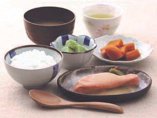 白いご飯に汁物、ブロック状のオレンジやグリーンの副菜、魚のような形のものが盛られている。