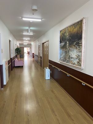 オールバリアフリーで手すりがついた施設内の廊下の様子。絵画がかかっている壁